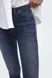 Close-up van de zak en textuur op de blauwe push-up jeans, met een wit overhemd erboven.