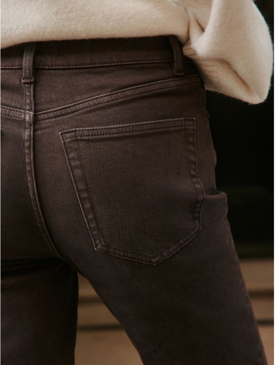 Close-up van de achterzakken van de bruine slim-fit jeans.