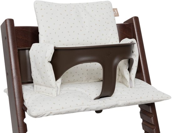 Donkerbruine stooletje met wit kussen met beige blaadjespatroon.