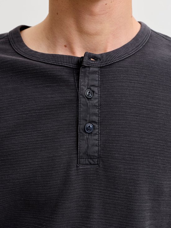 Close-up van een antracietgrijze henley-top met textuur en een knoopsluiting bij de ronde hals.