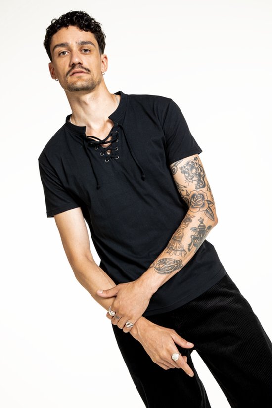 Man met tattoos en ringen draagt een zwart t-shirt met korte mouwen en veterdetail.