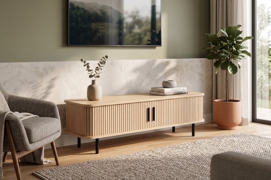 Eiken tv-meubel met verticale groeven, twee deuren met zwarte handgrepen en zwarte pootjes, in een woonkamer.