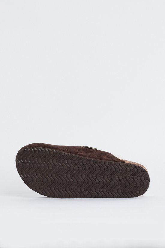 Semelle d'un sabot marron foncé en daim avec semelle extérieure ondulée.