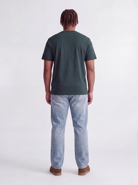 Model van achteren gezien in een donkergroen T-shirt en een spijkerbroek.