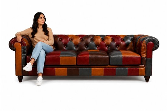 Een vrouw zit op een Chesterfield bank van leer met patchwork panelen in diverse kleuren.