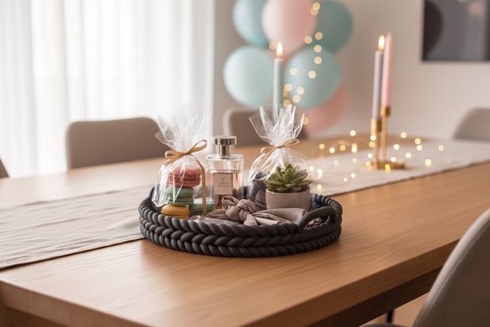 Zwart ovaal dienblad op tafel met cadeautjes, parfum en vetplant.