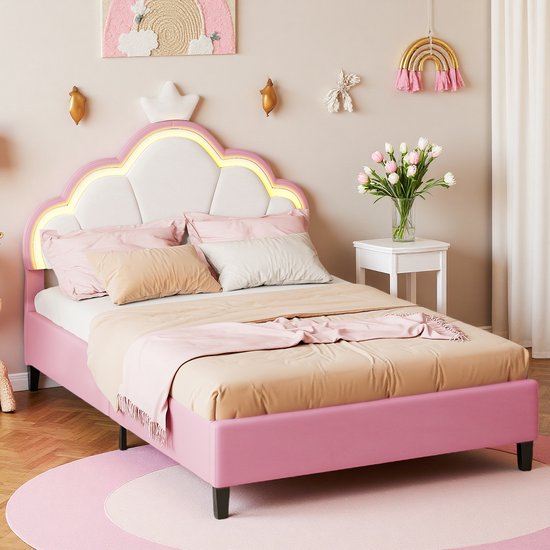 Roze gestoffeerd prinsessenbed met LED-verlicht kroonhoofdeinde en beige beddengoed, geplaatst op een rond roze kleed.