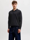 Man draagt zwart gebreid Jack & Jones poloshirt met lange mouwen en jeans.