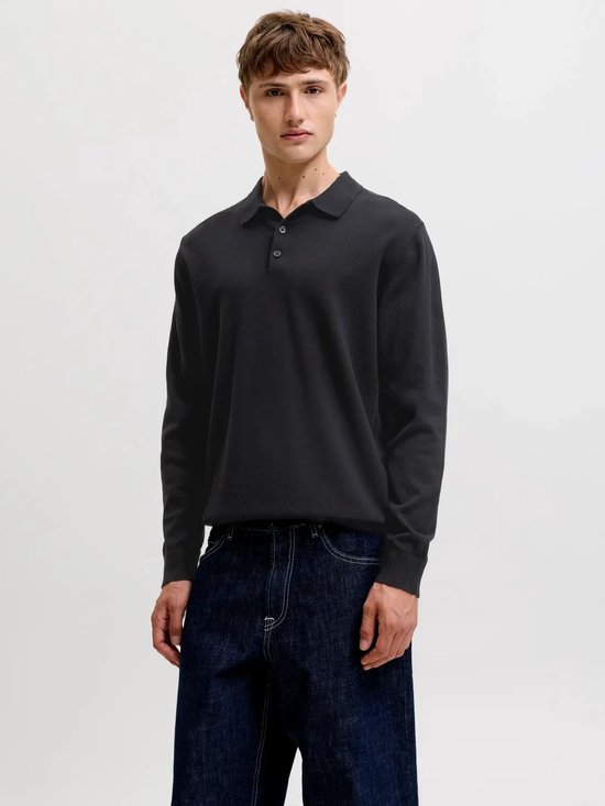 Man draagt zwart gebreid Jack & Jones poloshirt met lange mouwen en jeans.