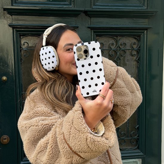 Vrouw met witte koptelefoon en witte telefoonhoes met zwarte stippen.