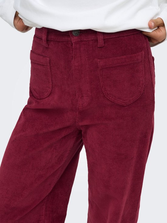Detail van de voorkant van een bordeauxrode corduroy broek met wijde pijpen en opgestikte zakken.