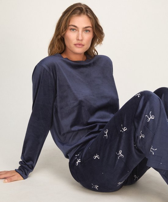 Model in een donkerblauwe pyjamabroek met strikjesprint.