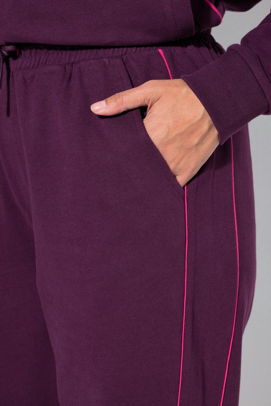 Detail van de zak van een donkerpaarse joggingbroek met roze bies.