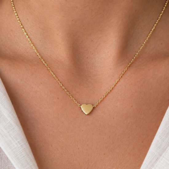 Gouden ketting met een klein, glanzend hartvormig hangertje op een dunne gouden schakelketting.