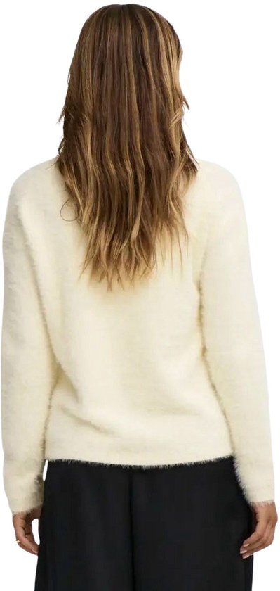 Model van achteren gezien met een crèmekleurige, pluizige trui en een zwarte broek.