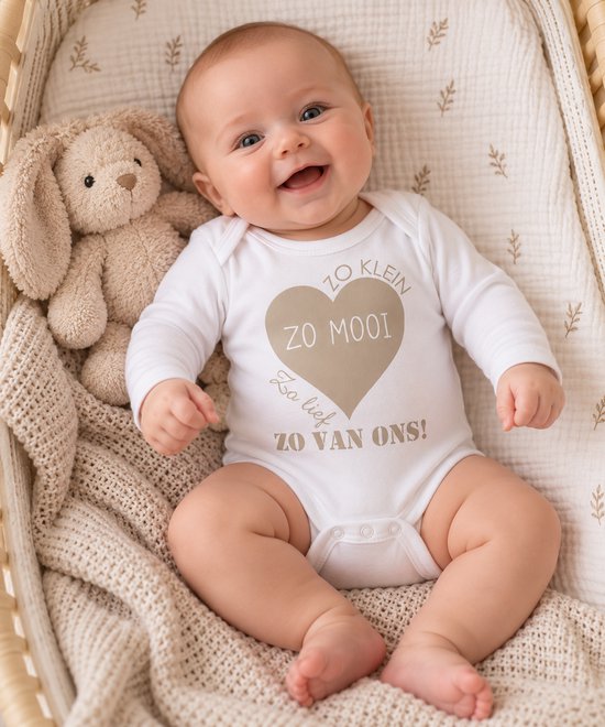 Lachende baby in witte romper met beige hart en tekst: Zo klein, zo mooi, zo lief, zo van ons, naast een beige knuffel.