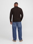 Achteraanzicht van een model in een bruine polo met lange mouwen, blauwe jeans en beige schoenen.