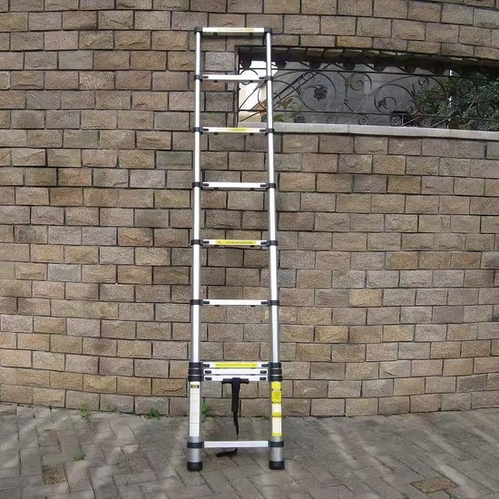 Uitgeschoven aluminium telescoopladder met 13 treden, zilverkleurig, tegen een stenen muur.