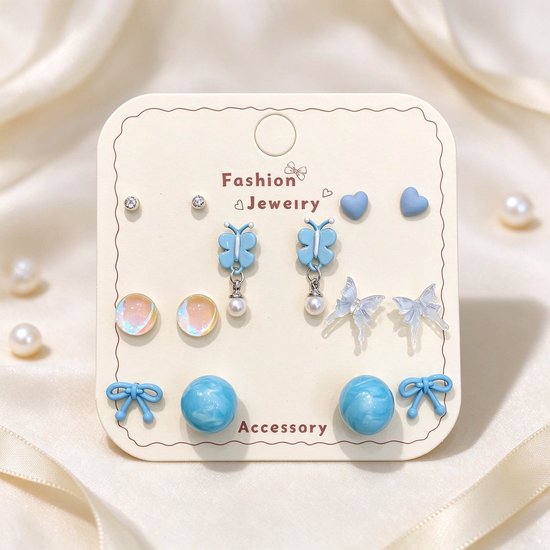 Set van 7 paar blauwe oorbellen inclusief hartjes, vlinders, parels en strikjes op een Fashion Jewelry kaart.