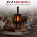 Zwarte buitenhaard met schoorsteen, brandend vuur en ruimte voor houtopslag. Mensen op terras.