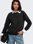 Zwarte sweater met opdruk 'PARIS' in glimmende steentjes, gedragen door een model met een wit overhemd eronder.