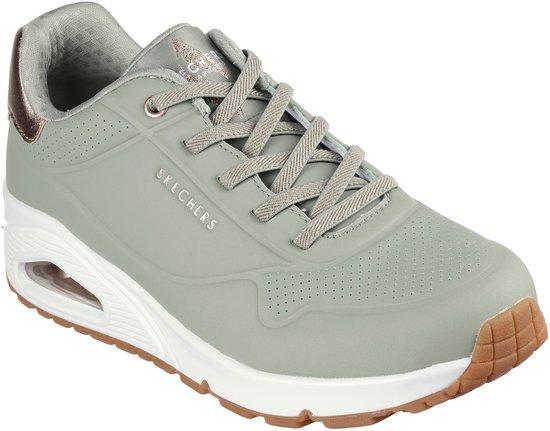 Lichtgrijze Skechers Uno sneaker met bruin-gouden accenten op de hiel en een witte zool.