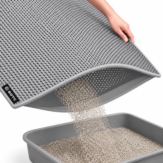 Grijze BOTC kattenbakmat met honingraatstructuur, toont dubbellaags ontwerp terwijl korrels terug in de bak vallen.
