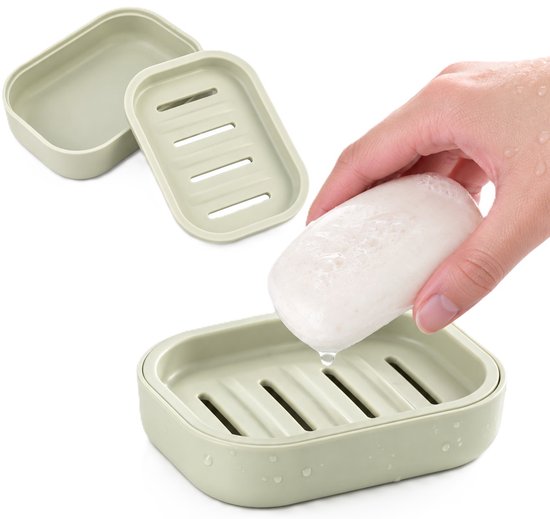 Une main tenant du savon le place dans une boîte à savon verte à double couche avec égouttoir.