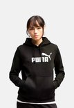 Model in een zwarte Puma hoodie met het witte logo op de borst, handen in de steekzakken.