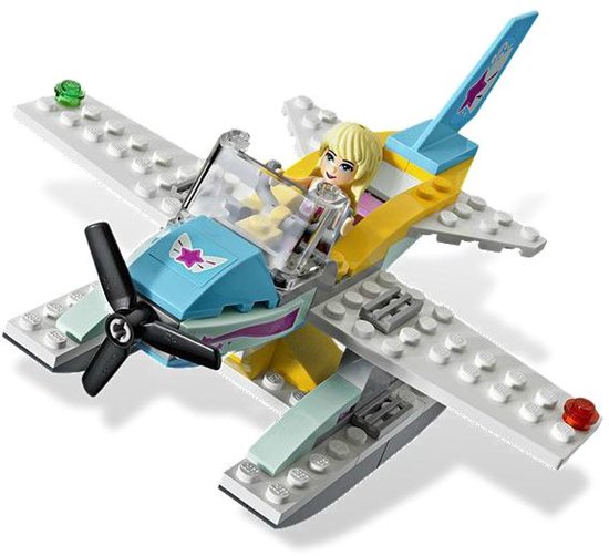 Wit en grijs watervliegtuig met blauwe en gele accenten, propellor, en een blond poppetje in de cockpit.