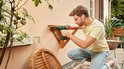 Man met veiligheidsbril bevestigt een houten plank aan een muur met de groene Bosch EasyDrill 18V-40.