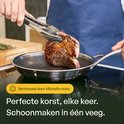 Chef-kok gebruikt een tang om een steak in een roestvrijstalen honingraatpan te draaien. Perfecte korst, elke keer.