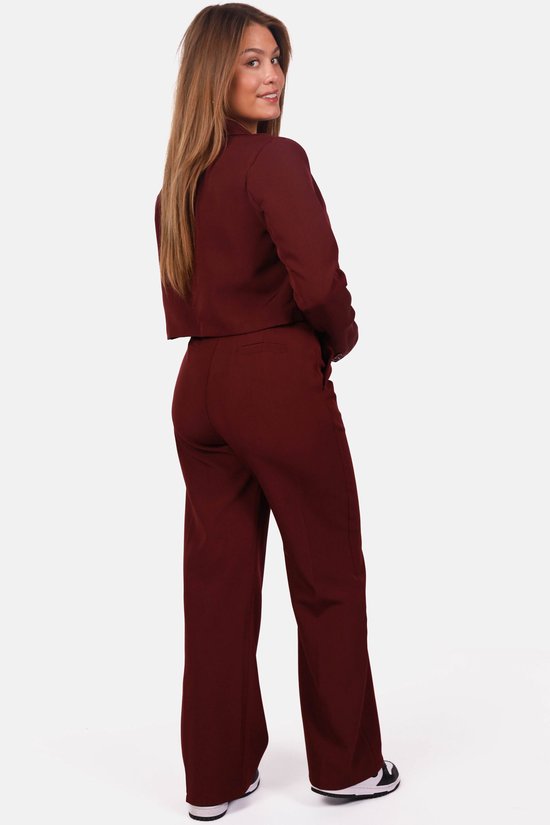 Achteraanzicht van het bordeauxrode broekpak met een cropped blazer en pantalon met wijde pijpen.