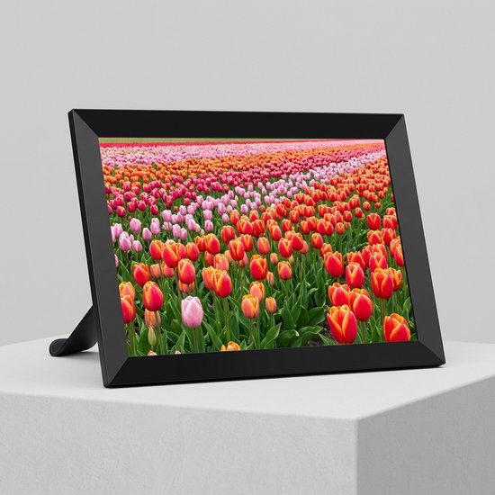 Cadre photo numérique noir sur un support blanc affichant une image colorée d'un champ de tulipes.