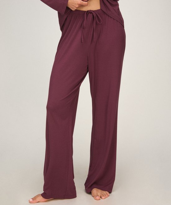 Close-up van een bordeauxrode pyjamabroek met trekkoord in de taille, gedragen door een model.