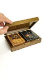 Hand tilt het deksel van een donkerbruine houten koffer met twee decks speelkaarten.