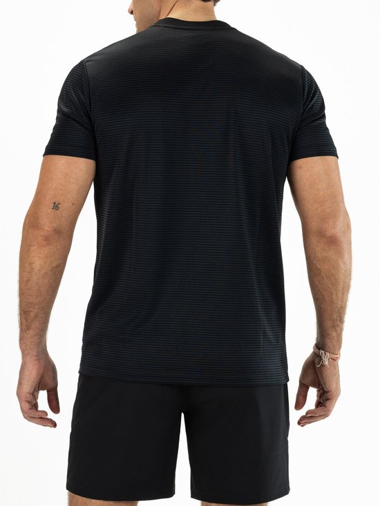 Achterkant van een man in een zwart sportshirt met fijne horizontale strepen en zwarte sportshorts.
