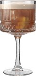 Een robuust cocktailglas met een brede voet, verticale ribbels en een diamantpatroon, gevuld met een goudbruine drank met schuim.
