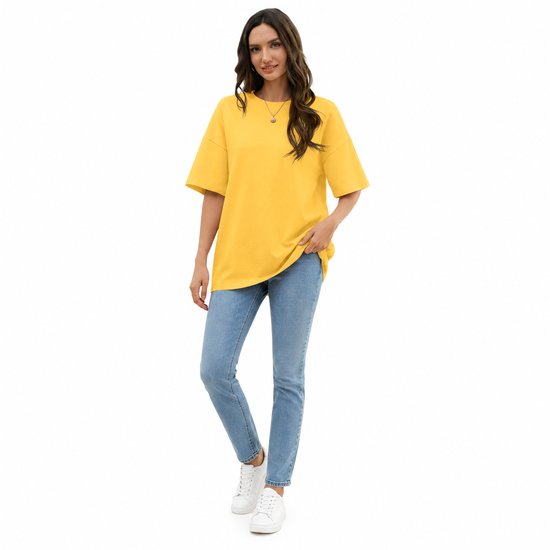 Model draagt oversized geel T-shirt met ronde hals, blauwe jeans en witte sneakers.