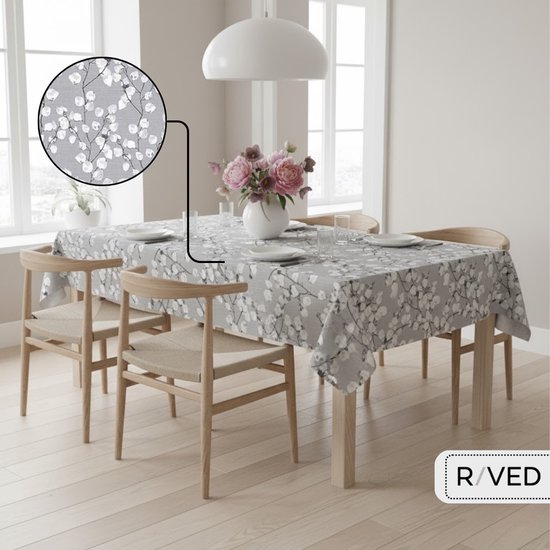 Grijze tafelzeil met witte lentebloesemprint, gedekt op een tafel in een eetkamer. Een detail van de print is ingezoomd.