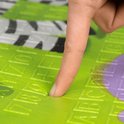 Vinger drukt in een zacht, groen speelkleed met reliëf.