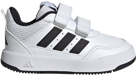 Witte peutersneaker van Adidas met zwarte strepen en klittenbandsluiting, gefotografeerd in een lege ruimte.