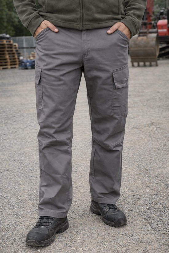 Pantalon de travail Snickers gris avec poches cargo sur les cuisses et genoux renforcés. Un homme porte le pantalon avec des chaussures de travail noires.