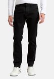 Man in zwarte jeans en witte longsleeve, staand.