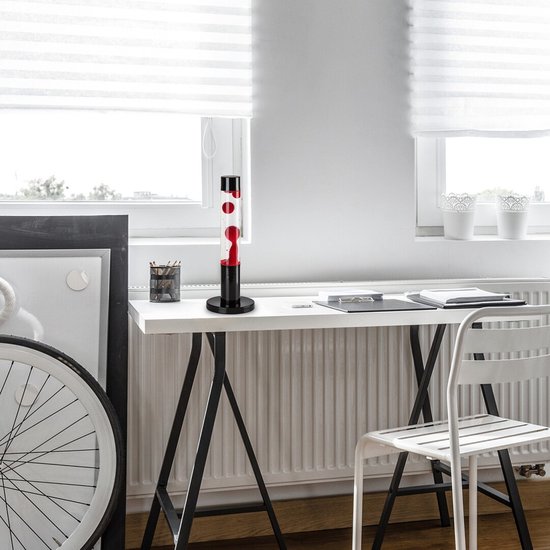 Een rode lavalamp op een bureau in een modern ingerichte kamer, met een zwarte voet en dop. Rode bellen bewegen in de lamp.