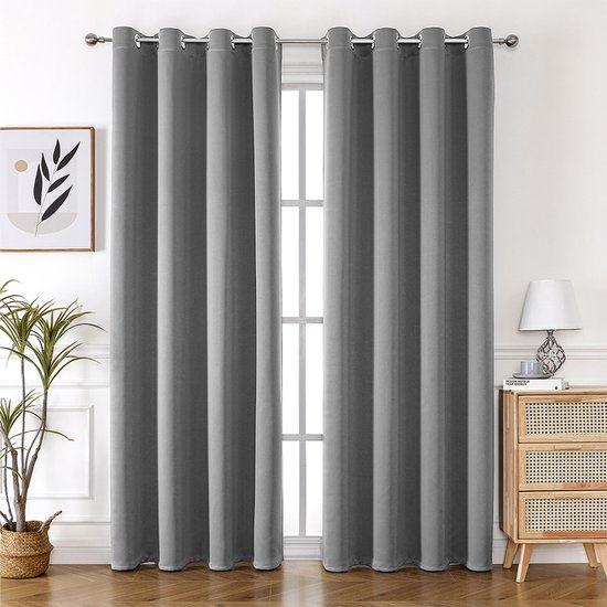 Lichtgrijze, verduisterende gordijnen met voering hangend voor een raam, met houten vloer en meubels.
