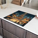 Inductiebeschermer met kerstdorp-print op een kookplaat in een moderne keuken.