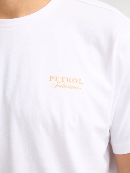 Close-up van de borst van een wit T-shirt met een kleine oranje opdruk van 'PETROL Industries'.