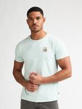 Man in lichtgroen T-shirt met een opgedrukte postzegel met bloemen op de linkerborst.
