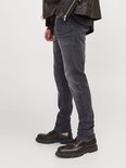 Man met grijze jeans en zwarte laarzen, de broek is opgerold aan de enkel.